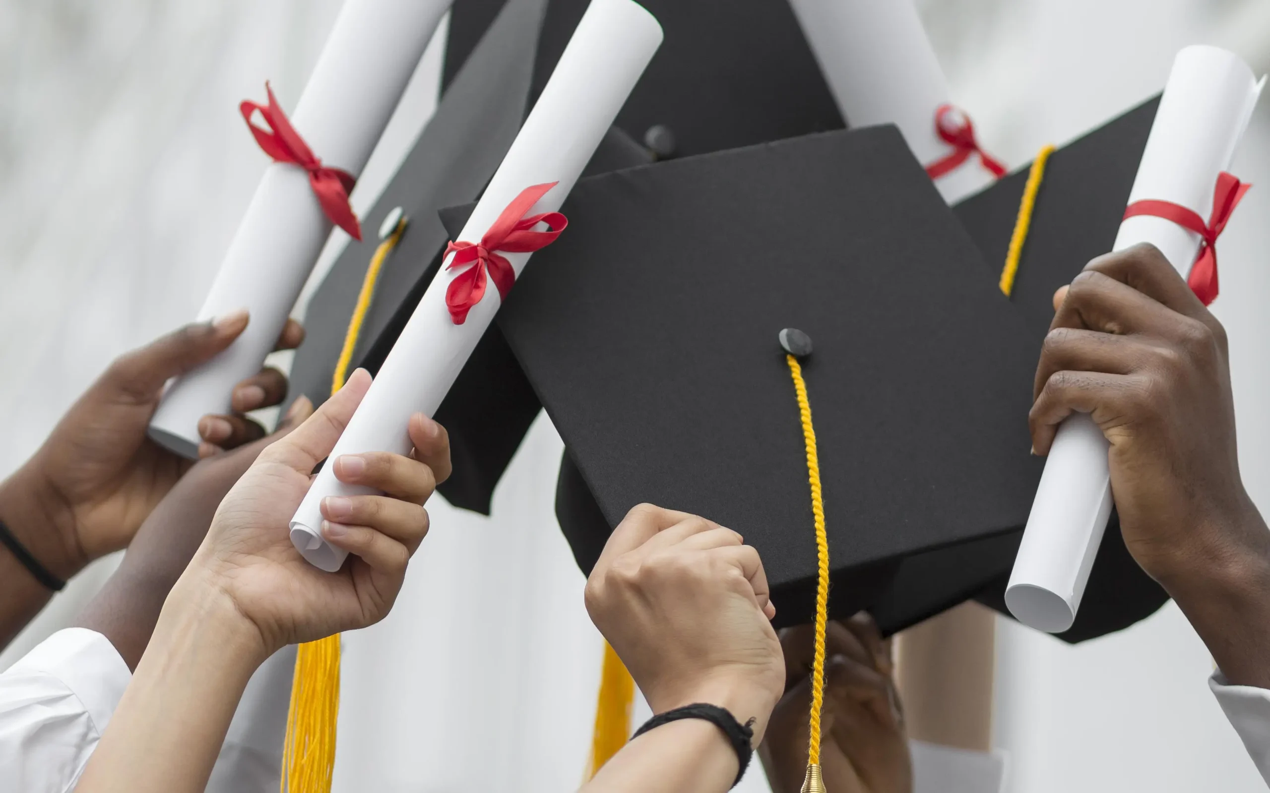 close-up-hands-holding-diplomas-caps close-up-hands-holding-diplomas-caps